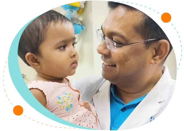 Prof. Dr. Salahuddin Mahmud smiling and interacting with a young child during a pediatric consultation